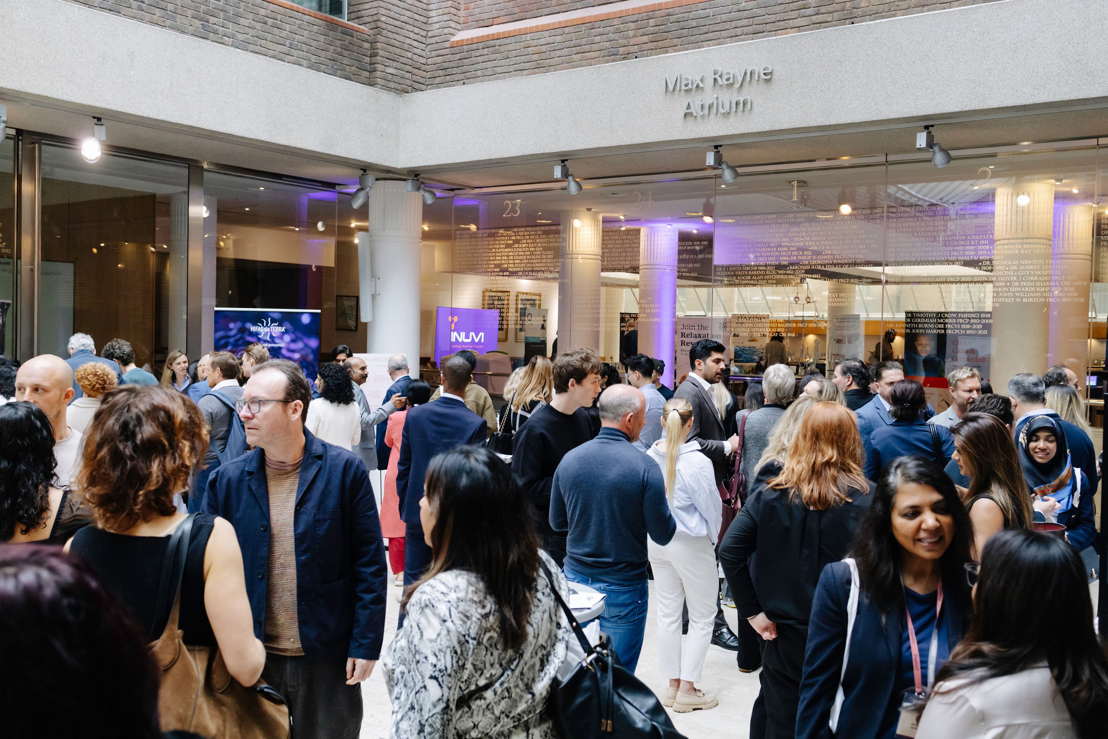 A busy crowd of attendees mingling in the Max Rayne Atrium at a Levitas event
